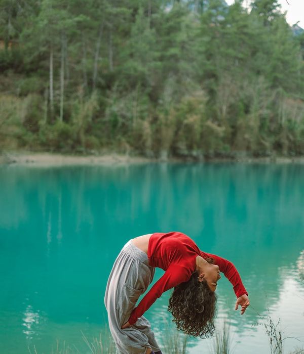 Woman in a calm yoga pose against a serene aqua background.